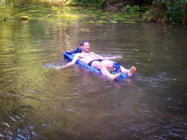 Mann liegt auf einer blauen Schwimmhilfe im Wasser und entspannt
