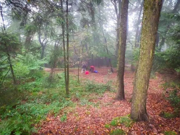 Personen sitzen auf dem Boden im Wald und arbeiten an Ausrüstung