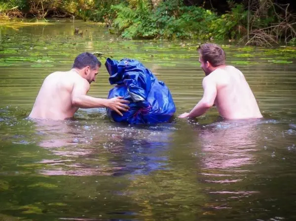Zwei Männer ziehen einen blauen Sack durch das Wasser