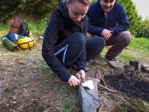 Feuerstahl erzeugt Funken auf Zunder, während eine Person sitzt und zündet