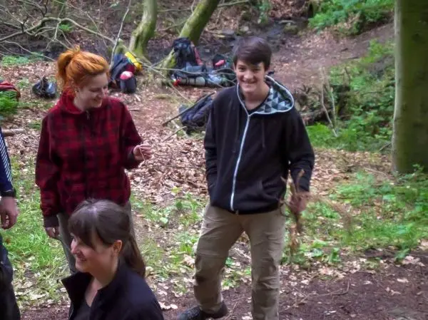 Gruppe von Personen im Wald, eine Person hält einen Stock in der Hand
