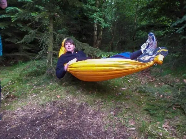 Hängematte zwischen Bäumen mit Person, die entspannt darin sitzt