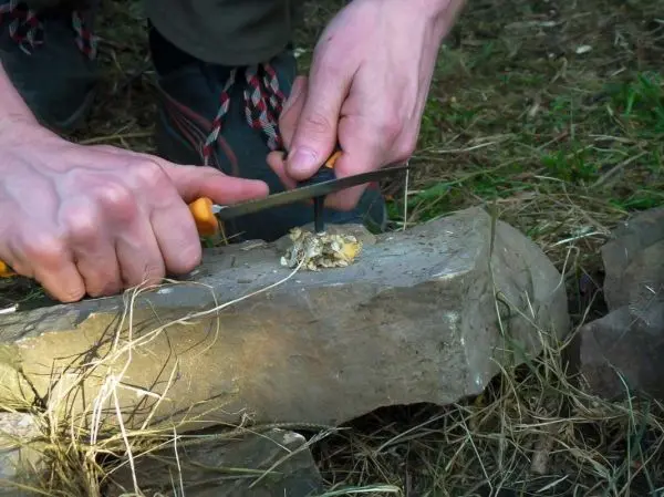 Messer schneidet Zunder auf einem großen Stein im Freien