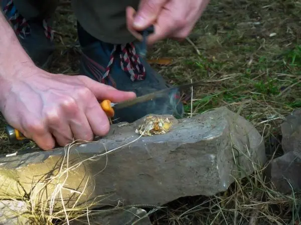 Messer schneidet Zunder auf einem Stein im Wald