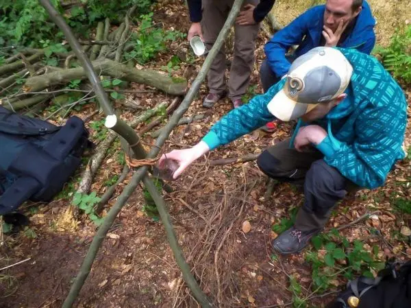 Person bindet Äste zusammen im Wald beim Survival Training