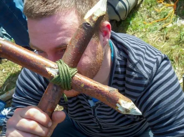 Person hält selbstgebaute Konstruktion aus Ästen vor das Gesicht