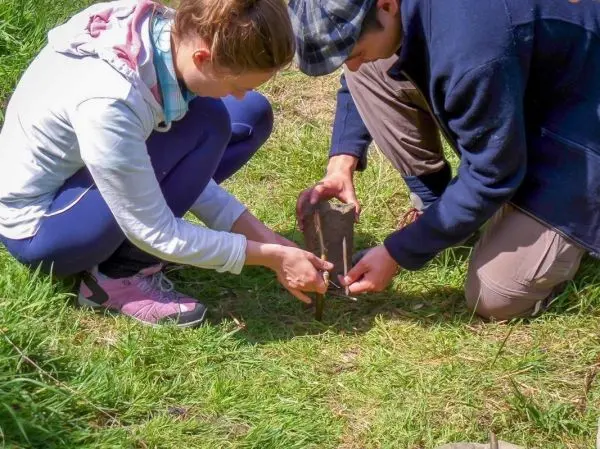 Personen bearbeiten einen Stein auf dem Boden