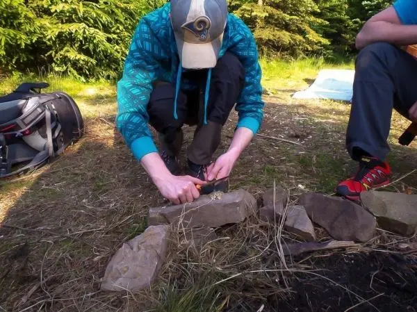 Zunder wird mit einem Messer auf Steinen bearbeitet