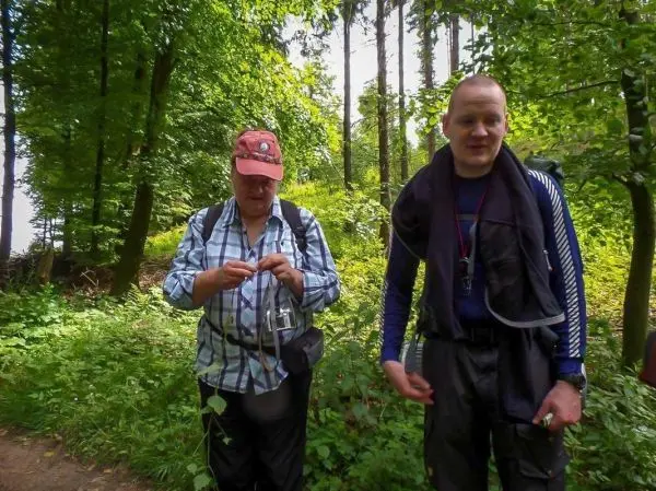 Zwei Personen stehen im Wald und halten Ausrüstung in den Händen
