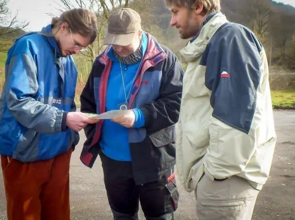 Drei Personen betrachten gemeinsam eine Karte im Freien