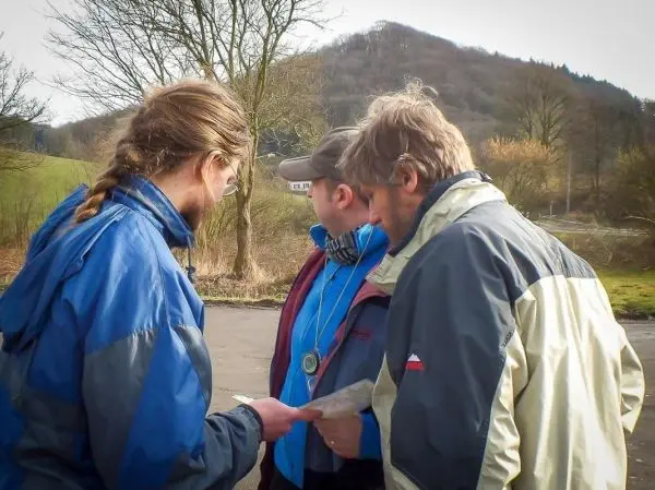 Drei Personen betrachten gemeinsam eine Karte im Freien