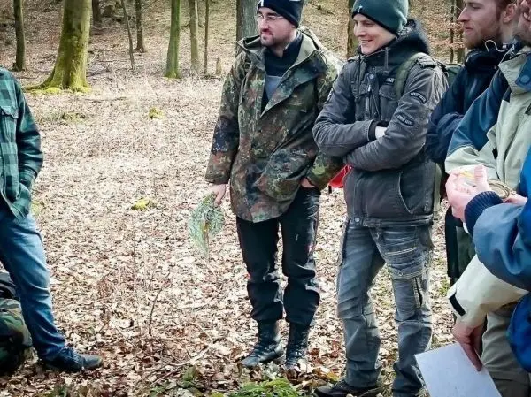 Gruppe diskutiert im Wald, einer hält eine Karte in der Hand