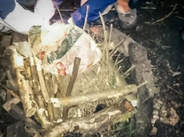 Kleine Flamme in einem improvisierten Feuerplatz mit Zunder und Holz