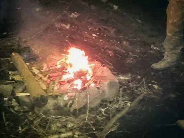 Kleine Flamme in einem Steinkreis, Rauch steigt auf