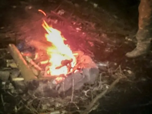 Kleine Flamme in einem Steinkreis, umgeben von Ästen und Holzstücken