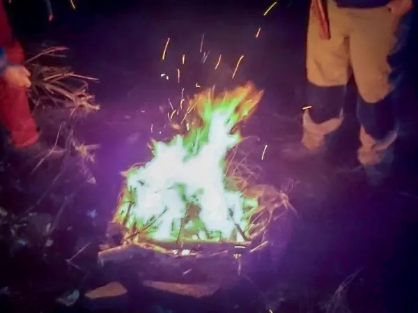 Kleine Flamme mit Funkenflug aus Zunder und Holzstücken in der Nacht