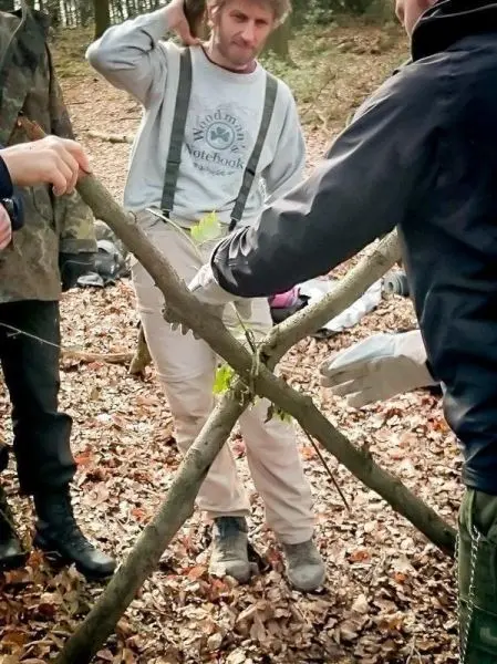 Person hält einen Stock, während andere einen Rahmen bauen