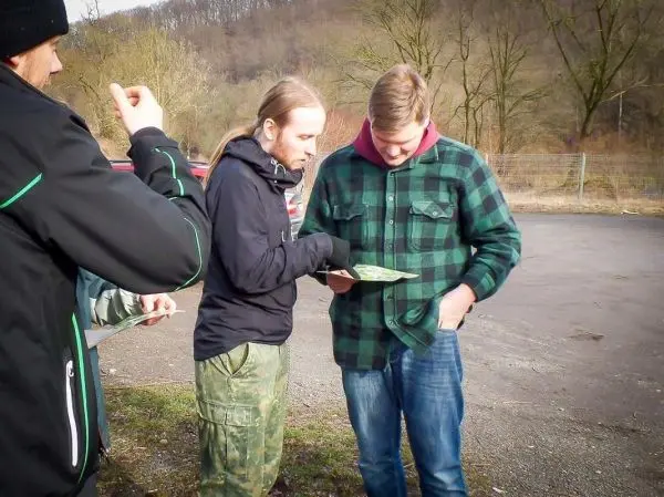 Zwei Personen betrachten eine Karte, während eine dritte Person im Hintergrund steht