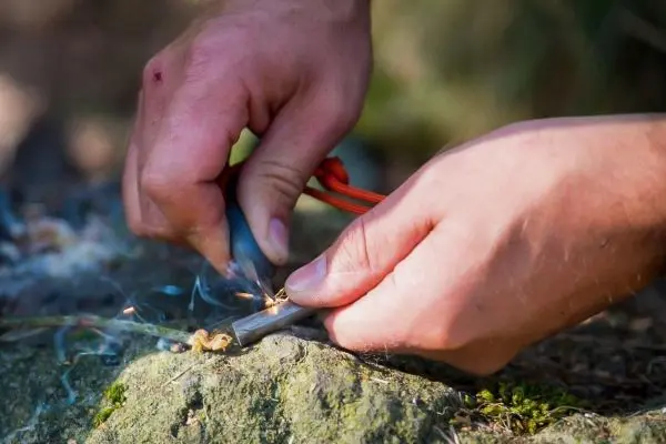Feuerstahl erzeugt Funken auf Zunder, während Rauch aufsteigt