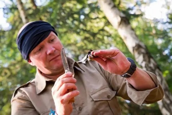 Person schneidet mit einem Messer etwas in der Hand
