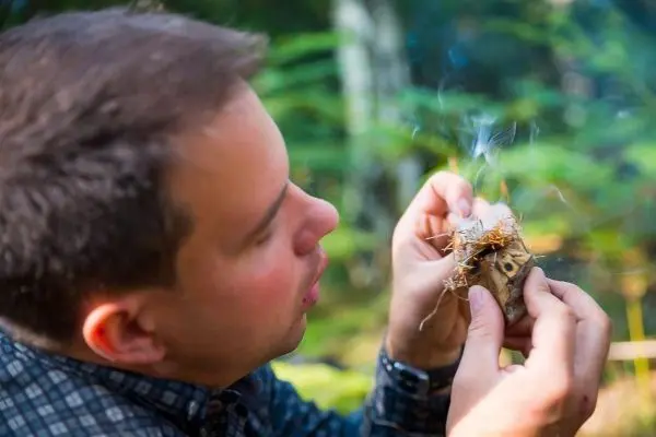 Zunder glimmt in den Händen, Rauch steigt auf