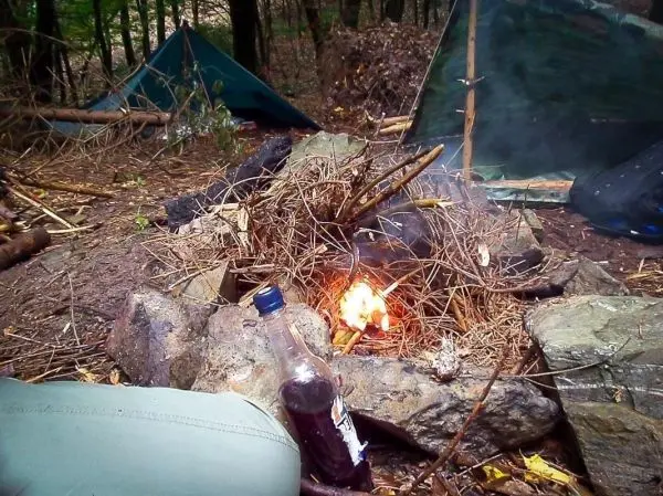 Feuerstelle mit brennenden Ästen und Steinen im Wald