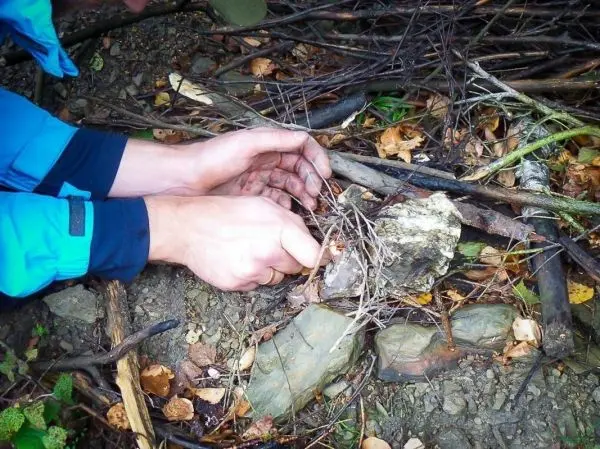 Hände bereiten Zunder auf dem Boden vor, um ein Feuer zu entfachen