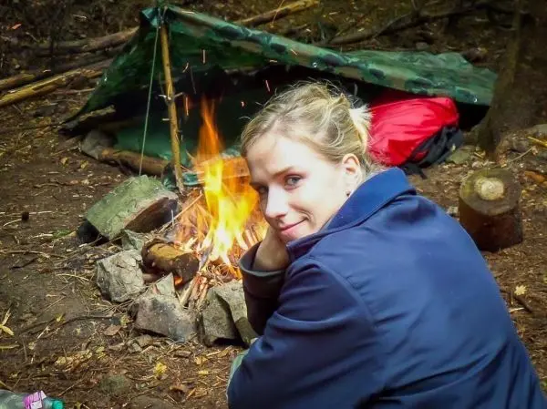 Kleine Flamme brennt in einem Steinkreis neben einer Tarp-Notunterkunft