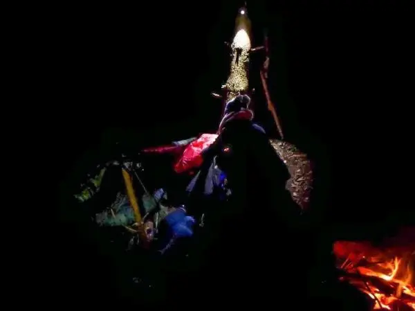 Kleine Flamme brennt neben Ausrüstung und einem Holzstock am Boden