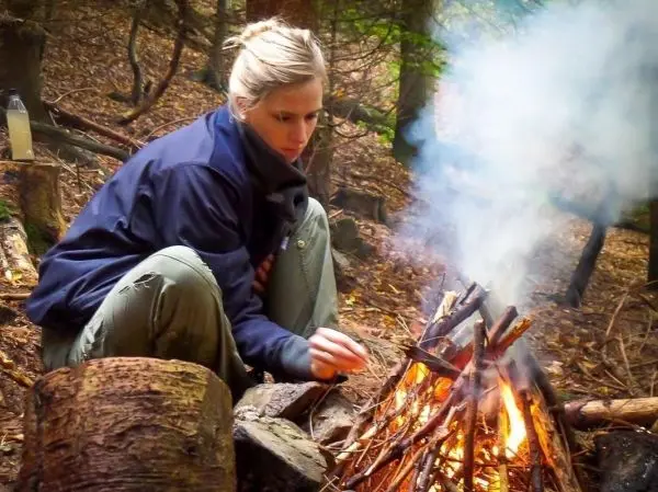 Kleine Flamme mit Rauch aus Holzscheiten im Wald