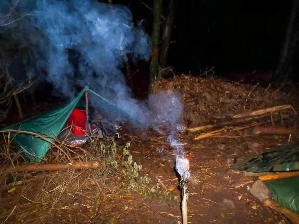 Kleine Flamme raucht aus einem improvisierten Feuerstelle auf einem Stock