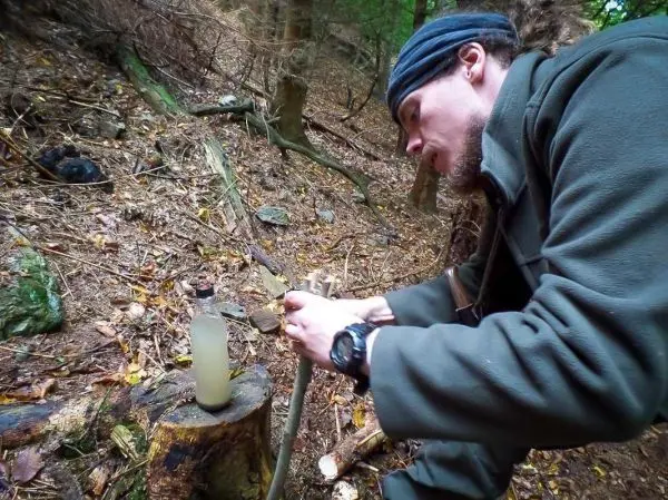 Mann bearbeitet einen Stock auf einem Baumstumpf mit einem Messer