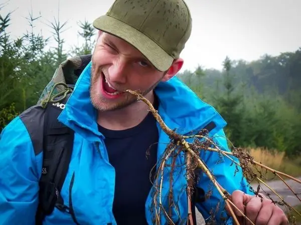 Mann hält eine Wurzel in der Hand und grinst in die Kamera