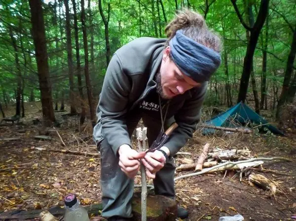 Messer bearbeitet Holzstück auf einem Baumstumpf im Wald