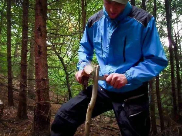 Messer bearbeitet Holzstück zur Herstellung eines Werkzeugs im Wald