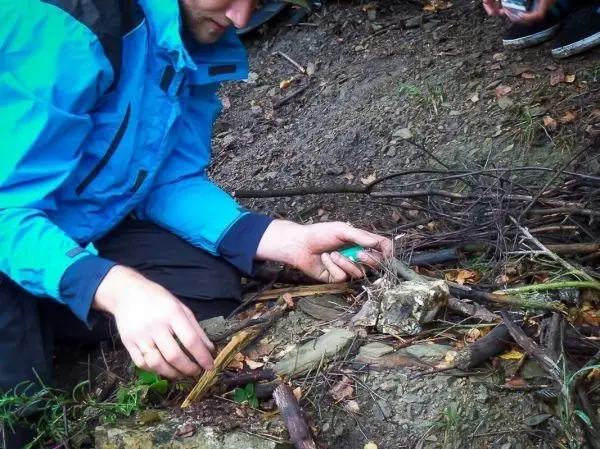 Person zündet Feuerstelle mit einem Feuerzeug an