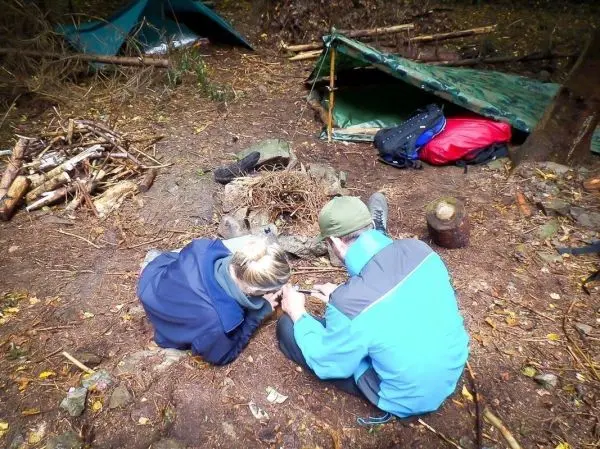 Personen bereiten Feuerstelle mit Zunder vor beim Survival Training