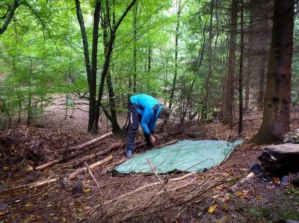 Tarp-Notunterkunft wird im Wald auf dem Boden ausgelegt