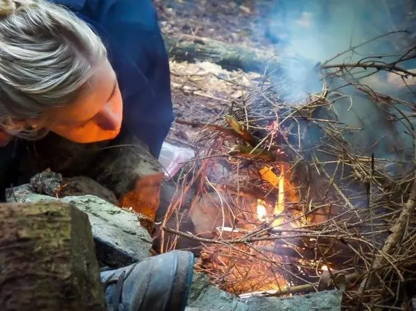 Zunder glimmt in einem kleinen Bodenfeuer zwischen Steinen