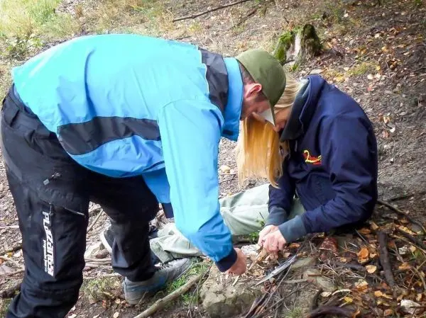 Zwei Personen arbeiten gemeinsam an einer Holzstruktur im Wald
