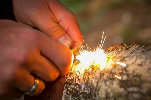 Feuerstahl erzeugt Funken auf einem Holzstück