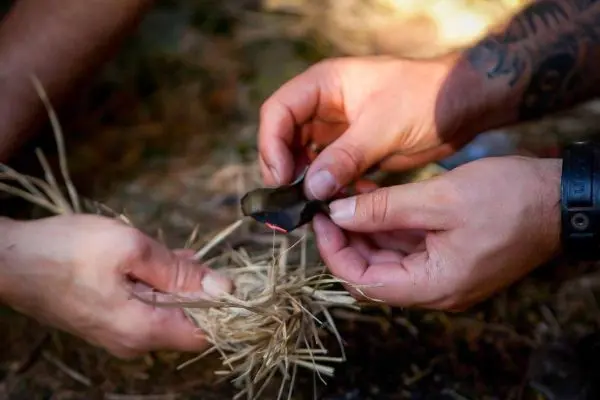 Feuerstahl erzeugt Funken auf Zunder aus trockenem Gras