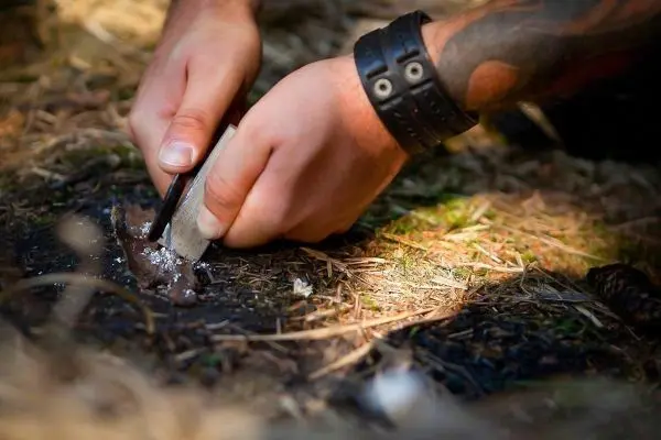 Feuerstahl erzeugt Funken auf Zunder im Boden