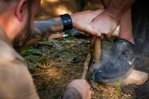 Hölzerne Feuerbohrer-Technik erzeugt Rauch durch Reibung auf einem Holzstück