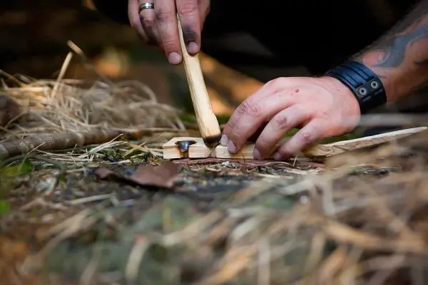 Holzstück wird mit einem Stock bearbeitet, um Funken zu erzeugen