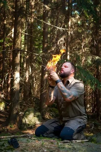 Kleine Flamme brennt in den Händen, während er Zunder hält