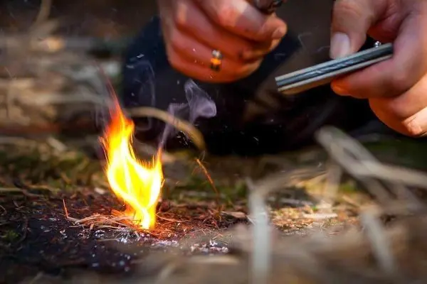Kleine Flamme entsteht aus Zunder während Feuerstahl Funken erzeugt