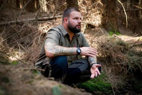 Kniend in einem Wald, erklärt jemand eine Technik mit gestikulierenden Händen