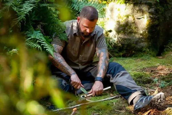 Messer bearbeitet Holzstück auf dem Boden im Wald