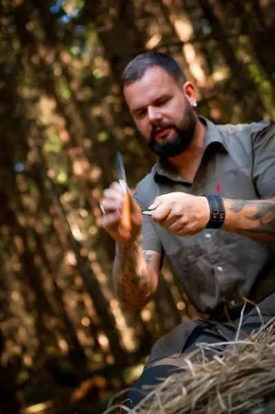 Person schnitzt mit einem Messer in einem Wald